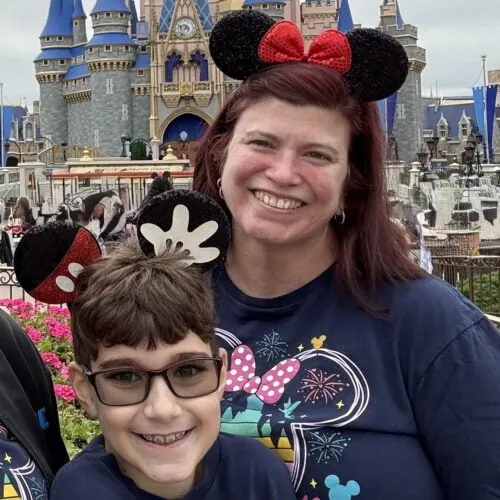 Jill and son wearing Mickey Mouse ears at Disneyland with castle in background.