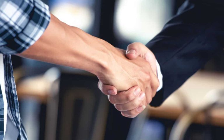 Handshake between two people in a professional setting, blurred background.